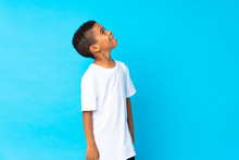 African American Boy Over Isolated Blue Background Looking Up While Smiling