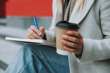 Wall Mural - Female student holding coffee to go outdoors