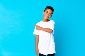 Wall Mural - African American boy over isolated blue background pointing to the side to present a product