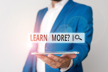 Poster - Conceptual hand writing showing Learn More question. Concept meaning gain knowledge or skill studying practicing Man in blue suite and white shirt holds mobile phone in hand