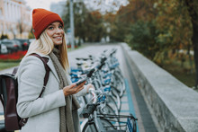 Happy Female Using Smartphone For Rental Bicycle
