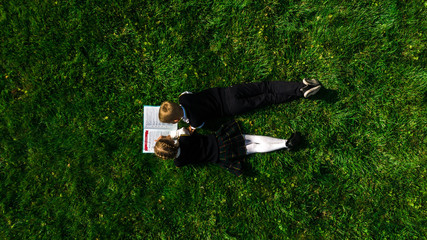 Children reading the book on the grass in summer. Top view