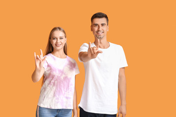 Wall Mural - Young deaf mute couple using sign language on color background