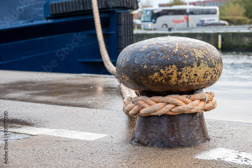 Fotografía a ship is attached with a thick rope to a bollard in the harbour