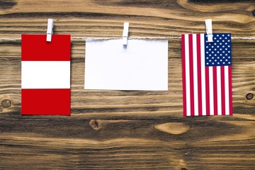 Wall Mural - Hanging flags of Peru and United States attached to rope with clothes pins with copy space on white note paper on wooden background.Diplomatic relations between countries.