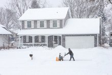 Man Using A Snowblower To Clear His Sidewalk And Driveway
