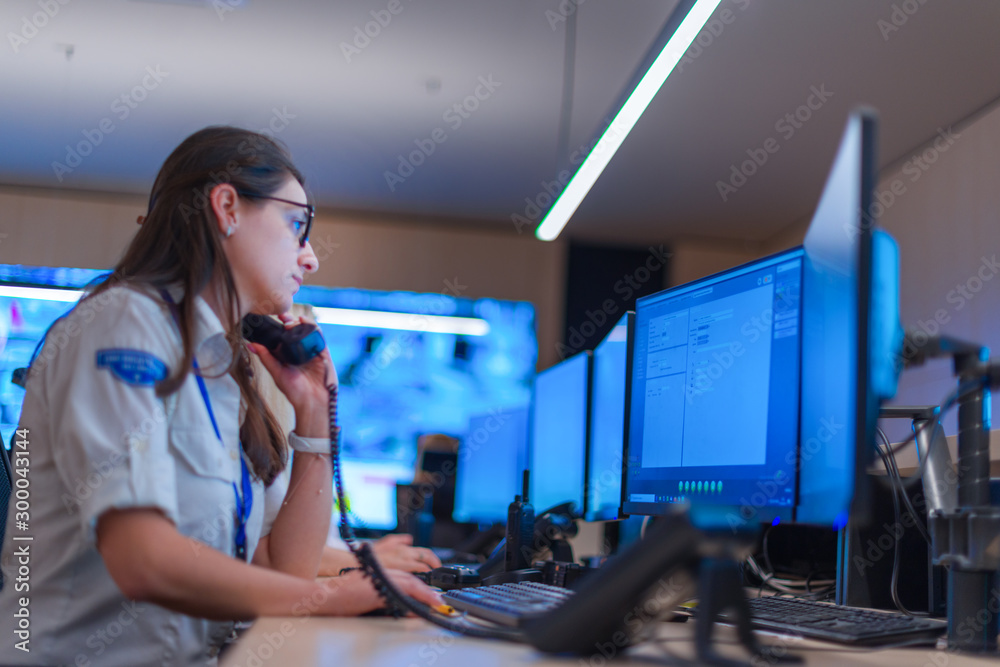 Female security guard operator talking on the phone while watching the ...