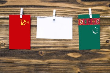 Hanging flags of Soviet Union and Turkmenistan attached to rope with clothes pins with copy space on white note paper on wooden background.Diplomatic relations between countries.