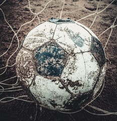 Dirty football old on the ground field after rain.