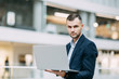 © pavelvozmischev - Office work, business situation. A young business man with a laptop in his hands.