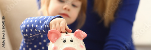 Cuadros en Lienzo Child little girl arm putting coins into piggybank