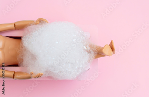 Photographie doll man legs in pink bath on pink pastel background