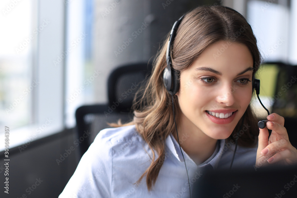 Beautiful smiling call center worker in headphones is working at modern office - obrazy, fototapety, plakaty 