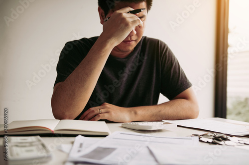 Fotomural Asian men are stressed about financial problems, with invoices and calculators placed on the table while having stress on problems with home expenses