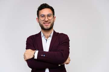 Men's fashion concept. Portrait of a handsome male model in glasses shows hands wearing a dark jacket, posing on a gray background. Black hair. Close Studio Shot