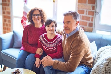 Beautiful family smiling happy and confident. Sitting on the sofa with smile on face hugging around christmas decorations at home