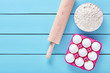 Ingredients for baking, eggs, flour and rolling pin on blue wooden background