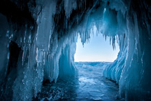 View from the ice cave on Lake Baikal. Many beautiful icicles on the walls and ceiling. Thick and thin icicles. Ice on the floor.