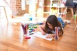 © Krakenimages.com - Adorable toddler lying down on the floor drawing using paper and pencils at kindergarten