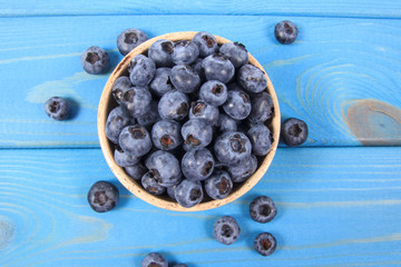 Raw fresh huckleberry in a bowl. Wooden background.