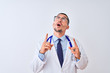 © Krakenimages.com - Young doctor man wearing stethoscope over isolated background amazed and surprised looking up and pointing with fingers and raised arms.