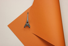 Statuette Of The Eiffel Tower On A Colored Paper Background. Top View