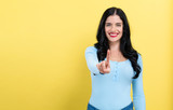 Fototapeta Na ścianę - Young woman pointing at something on a yellow background