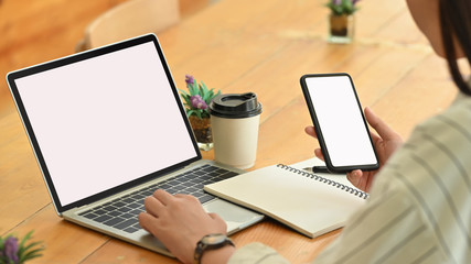 Female using isolated smartphone and laptop computer.