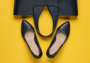 Classic high heel shoes, leather bag on yellow background. Minimalism fashion concept. Top view