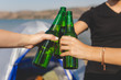 © zphoto83 - Friends clinking bottles of beer on beach camping picnic.