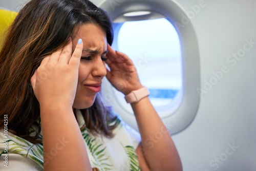 Fotomural Young traveller woman sitting inside plane at the airport with sky view from the