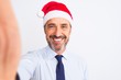 © Krakenimages.com - Middle age businessman wearing christmas hat make selfie over isolated white background with a happy face standing and smiling with a confident smile showing teeth