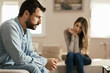 © Goran - Young man feeling sad after arguing with his girlfriend on sofa at home
