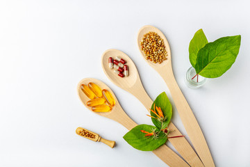 Herbal capsule, natural vitamins, dry calendula flowers at wooden spoon on white background. Concept of healthcare and alternative medicine: homeopathy and naturopathy. Flat lay, copy space