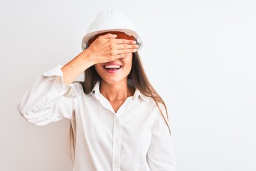 Poster - Young beautiful architect woman wearing helmet and glasses over isolated white background smiling and laughing with hand on face covering eyes for surprise. Blind concept.