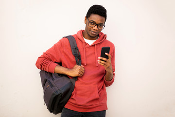 young african american man with glasses and bag holding mobile phone by white background