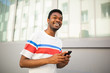 © mimagephotos - Close up of young smiling african american man walking with mobile phone