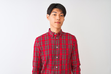 Young chinese man wearing casual red shirt standing over isolated white background Relaxed with serious expression on face. Simple and natural looking at the camera.