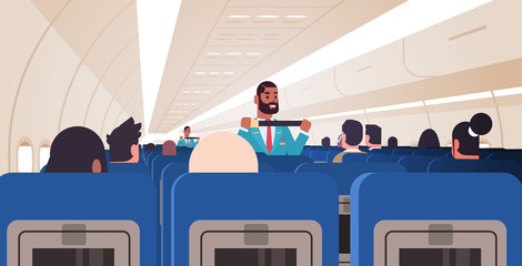 Wall Mural - steward explaining passengers how to use seat belt fastening in emergency situation african american flight attendants in uniform safety demonstration concept airplane board interior horizontal vector