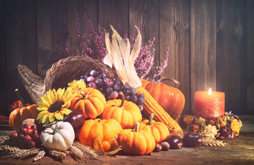 Pumpkins with fruits and falling leaves on rustic wooden table