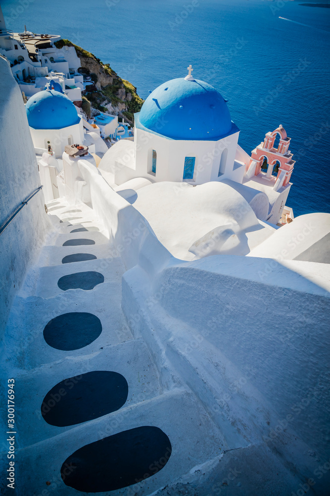 Traditional white architecture and greek orthodox churches with blue domes over the Caldera in Aegean - obrazy, fototapety, plakaty 