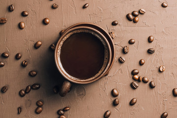 Brown Coffee cup with coffee beans on brown textured background. Top view. Copy space. Flat lay