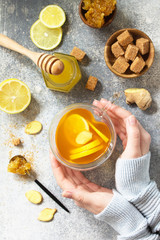 Wall Mural - Woman holds a hot cup of ginger tea. Top view flat lay.