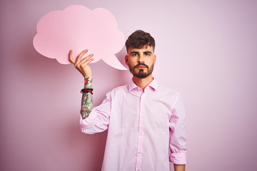 Sticker - Young man with tattoo holding cloud speech bubble standing over isolated pink background with a confident expression on smart face thinking serious