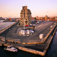 View of a quay of the port of Livorno at sunset. Old abandoned building. Industrial archeology.