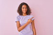Young brazilian woman wearing t-shirt standing over isolated pink background Pointing aside worried and nervous with forefinger, concerned and surprised expression