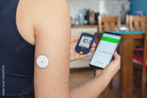 Fotomural Woman comparing result of glucose level check on the traditional glucometer and