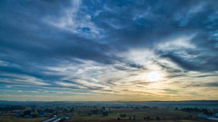 Wall Mural - Aerial View of a Late Afternoon Sun With Partly Cloudy Blue Sky Over Farm Countryside Background