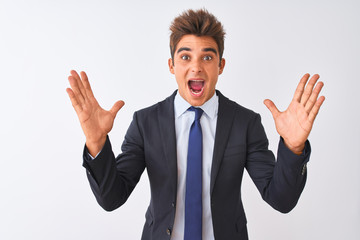 Young handsome businessman wearing suit standing over isolated white background celebrating crazy and amazed for success with arms raised and open eyes screaming excited. Winner concept