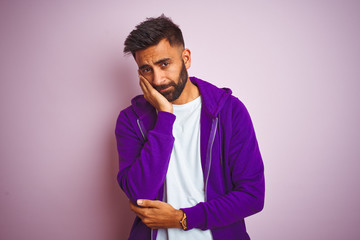 Wall Mural - Young indian man wearing purple sweatshirt standing over isolated pink background thinking looking tired and bored with depression problems with crossed arms.